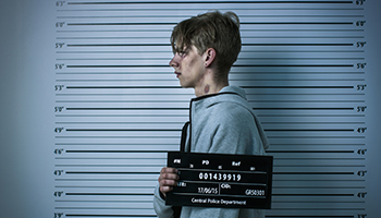 A man stands in front of a mug shot backdrop